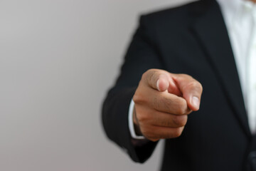 A business man in a suit is using his index finger to give a command or order.