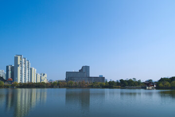 Fototapeta na wymiar Distant view of tall buildings in a city by the lake under the blue sky
