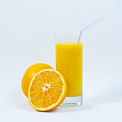 Close up of a glass of orange juice with a straw in a white background with fresh oranges, a delicious drink