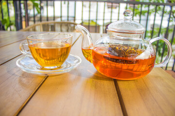 Teapot and Cup Of Hot Tea a wooden table outdoors morning narrow depth of field
