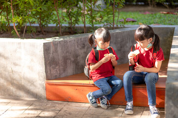 Kids eating outdoors at the school. Healthy school breakfast for children. Sandwich time.