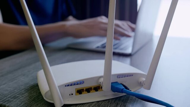 A man is working at home using a modem router, connecting the Internet to his laptop.