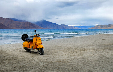 yellow scooter from bollywood movie parking at highest salt lake in the world with mountain background at Pangong Lake
