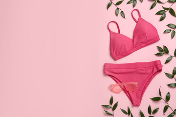 Stylish bikini, sunglasses and green leaves on pink background, flat lay. Space for text