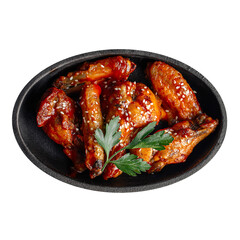 Isolated cast iron plate of fried chicken wings in teriyaki sauce