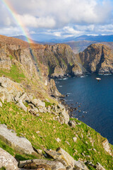 Obraz premium Rock face by the sea with a rainbow