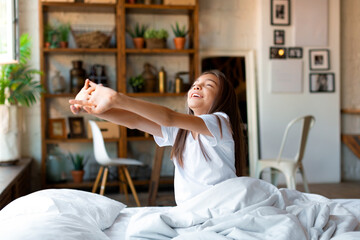 Ten-year-old girl woke up and, stretching. She stretched her arms up and enjoys the day off.