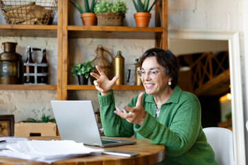 Smiling senior woman filling forms online in home interior. Online working from home. - Powered by Adobe