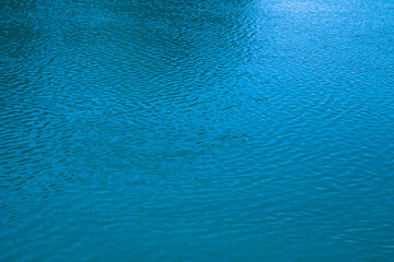 Fototapeta na wymiar Blue water background. The calm surface of the sea. Ocean. Natural abstract background. Film grain and noise.