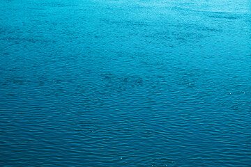 Blue water background. The calm surface of the sea. Ocean. Natural abstract background. Film grain and noise.