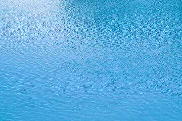 Blue water background. The calm surface of the sea. Ocean. Natural abstract background. Film grain and noise.