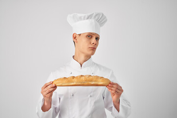 a man in a chef's uniform with a loaf in his hands fresh food work light background