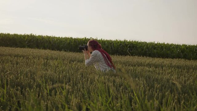 Girl takes photos on the green wheat field