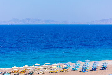 Obraz premium Colorful umbrellas and sunbeds on an empty beach resort - vacation concept on Greece islands in Aegean and Mediterranean seas