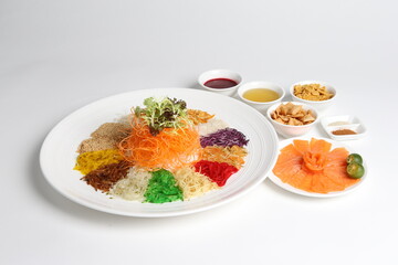 chinese new year colourful lo hei yu sheng with smoked salmon, vegetables and sauces in white gold background asian halal menu for cny festival