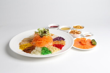 chinese new year colourful lo hei yu sheng with smoked salmon, vegetables and sauces in white gold background asian halal menu for cny festival
