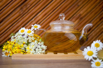 Obraz na płótnie Canvas A teapot of herbal tea with chamomile. Green tea. Chamomile flowers, wildflowers