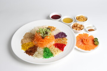 chinese new year colourful lo hei yu sheng with smoked salmon, vegetables and sauces in white gold background asian halal menu for cny festival