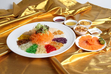 chinese new year colourful lo hei yu sheng with smoked salmon, vegetables and sauces in white gold background asian halal menu for cny festival