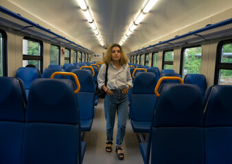 Beautiful young girl stands inside the train and looks directly at the camera