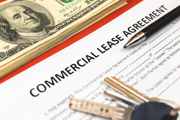 Commercial lease agreement form close-up. House keys, pen and money on office desk. Close-up