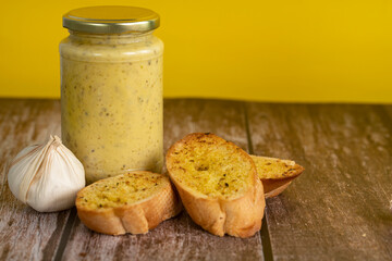 A few slice of garlic bread with a jar of garlic butter spread. Selective focus points. Blurred background