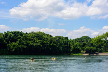 Fototapeta na wymiar 青空の下、ゆったりとした川の中を黄色い小さなレジャーボートが行く