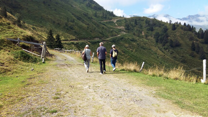 middle-aged people walking together. A man and two women having a health activity in the nature (italian Alps mountains) © missizio01