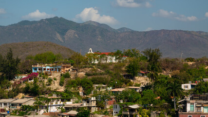 Cuban poor colorful village with church on the hill near city Santiago de Cuba  