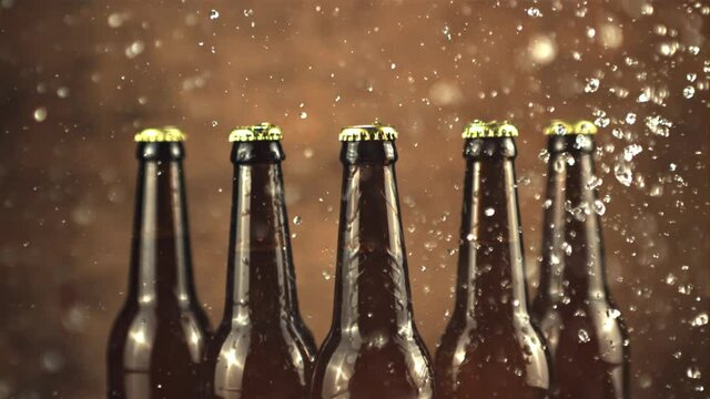 Super slow motion glass beer bottles with water splashes. On a brown background. Filmed on a high-speed camera at 1000 fps.