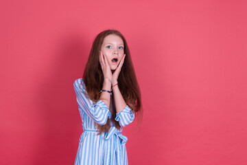 Little kid girl 13 years old in blue dress isolated on pink background shocked look to camera