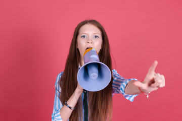 Little kid girl 13 years old in blue dress isolated on pink background shouting in megaphone...