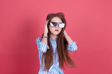 Little kid girl 13 years old in blue dress with brackets isolated on pink background wearing 3d cinema glasses shocked