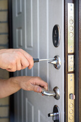 Repairing the door lock with a screwdriver. Close up, vertical
