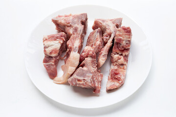 Raw pork bone in white plate on white background.