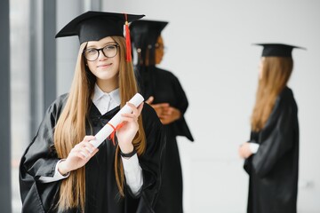 Beautiful female graduate standing out from a group of students