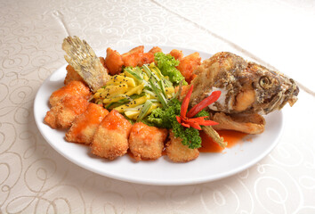 deep fried whole grouper fish seafood with sweet and sour sauce & mango salad in the middle asian halal menu