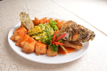 deep fried whole grouper fish seafood with sweet and sour sauce & mango salad in the middle asian halal menu