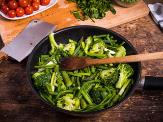 Cooking primavera pasta - green vegetables: beans, broccoli and asparagus in a pan, top view