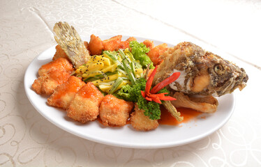 deep fried whole grouper fish seafood with sweet and sour sauce & mango salad in the middle asian halal menu