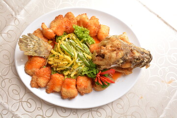 deep fried whole grouper fish seafood with sweet and sour sauce & mango salad in the middle asian halal menu