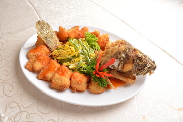 deep fried whole grouper fish seafood with sweet and sour sauce & mango salad in the middle asian halal menu
