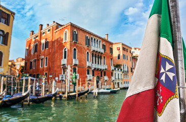 Italian maritime flag and Venetian Renaissance waterfront palaces, gondola stations, Venice, Italy. Travel destinations, UNESCO world heritage 