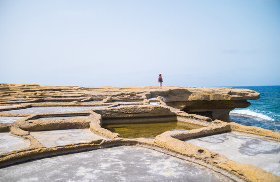 Young woman walking or hiking the Mediterranean Salinas, Xwejni Salt Pans in Gozo in Malta.