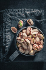 Tasty pistachios in rustic metal cup. Quick and good snack.