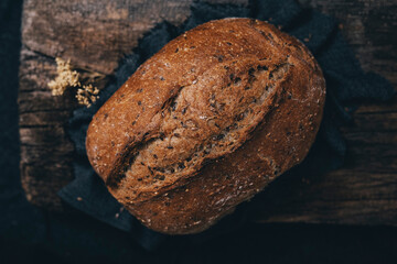 Top view of wholemeal rye bread with many seeds in its composition placed on a wooden surface.