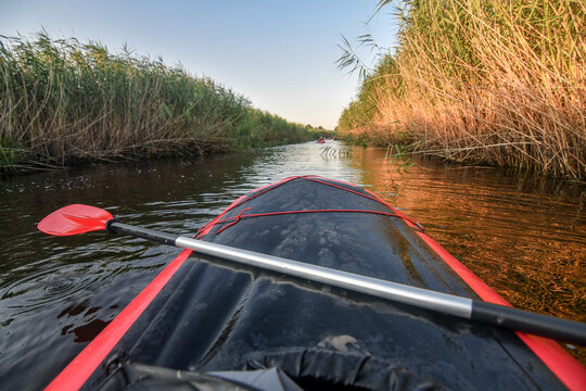 Paddling in red kayak on the river at sunset. Selective focus. Active lifestyle concept.