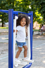 Outdoor portrait of curly smiling african american girl on a sports simulator.