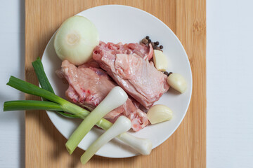 Chicken with vegetables on a white plate is ready for cooking soup.