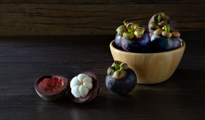 Fresh mangosteen Thai fruits in wooden bowl put on wooden table and old wooden wall